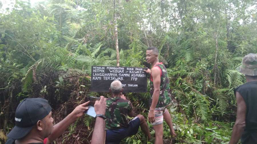 Aksi-pemasangan-papan-kayu-dengan-tulisan-menolak-peningkatan-jalan-hotmix-weduar-–-kilwat-langgiar-feer-yang-melewati-tutrean